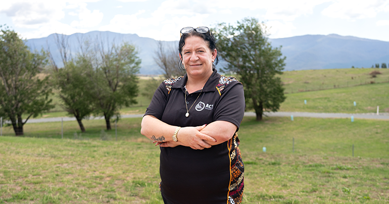 Female Yurauna student standing outside with trees and mountians in the background